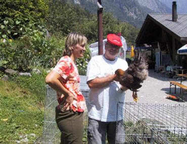 Kleintierzüchterin und Kleintierzüchter halte Huhn in der Hand und diskutieren
